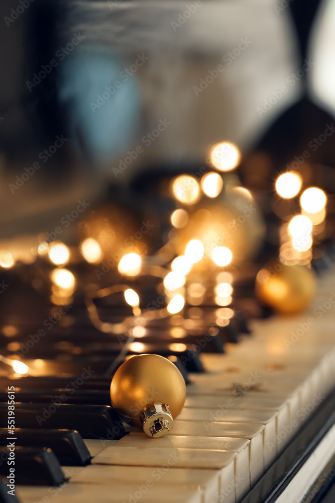 Christmas ball with glowing lights on piano keys, closeup