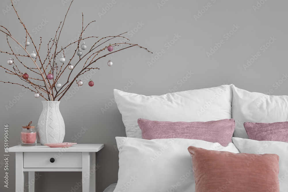 Vase with tree branches, Christmas balls, candle and jewelry on table in bedroom