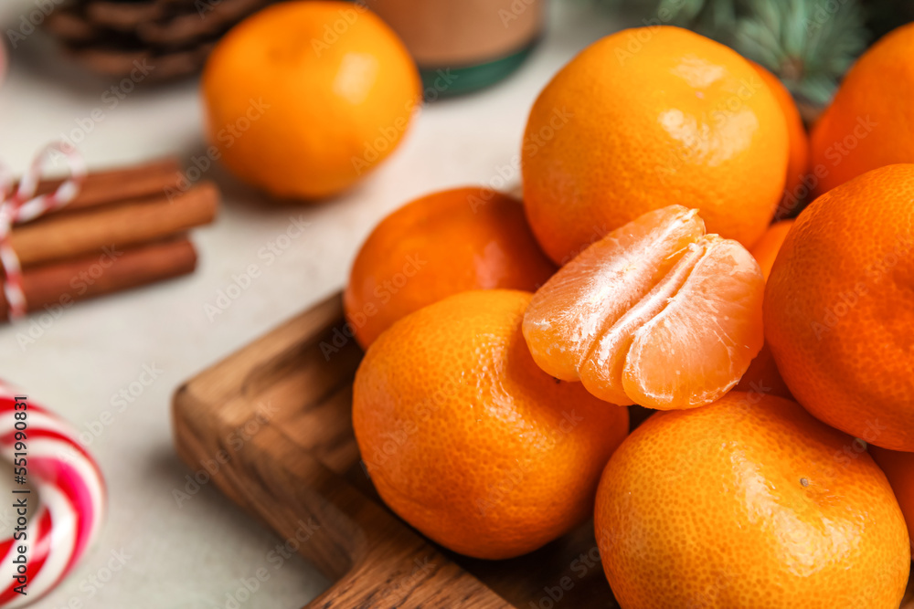 Wooden board with ripe tangerines on table, closeup