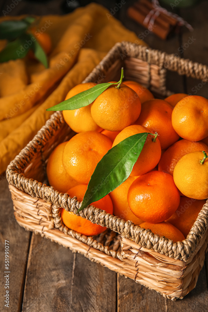 Basket with ripe tangerines on wooden table, closeup