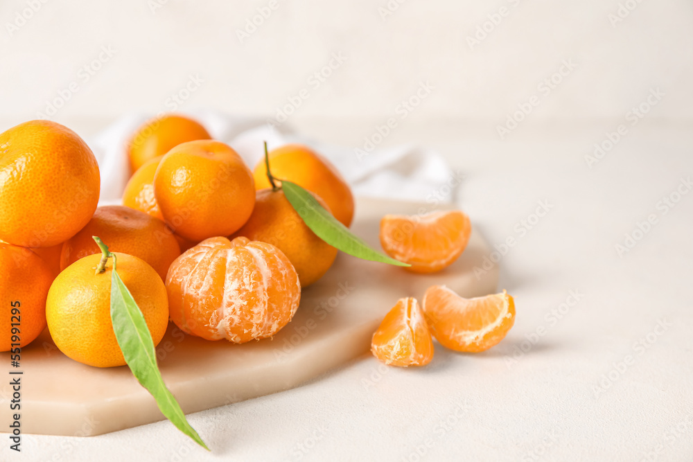 Board with fresh ripe tangerines on light background