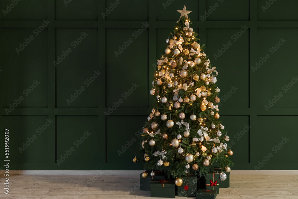 Glowing Christmas tree with presents near green wall