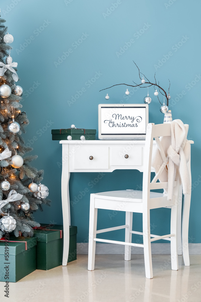 Vase with tree branches, Christmas balls, laptop and gift on table in office