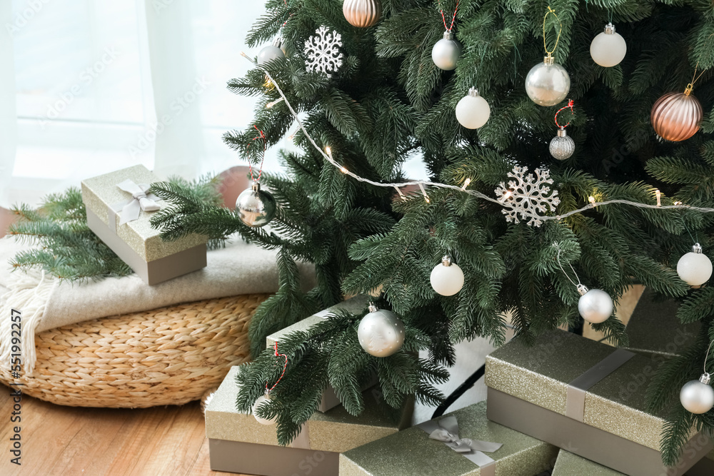 Decorated Christmas tree with pouf and presents in living room, closeup