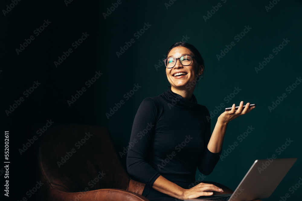 Young woman with laptop talking on phone