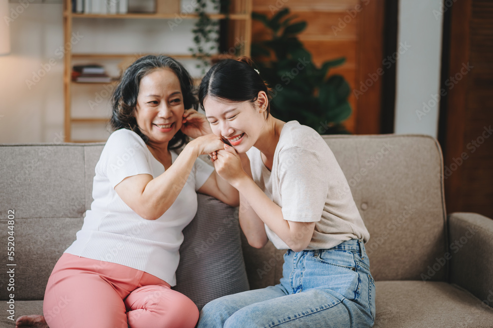 快乐的成年孙女和老奶奶在现代生活中坐在沙发上享受聊天乐趣