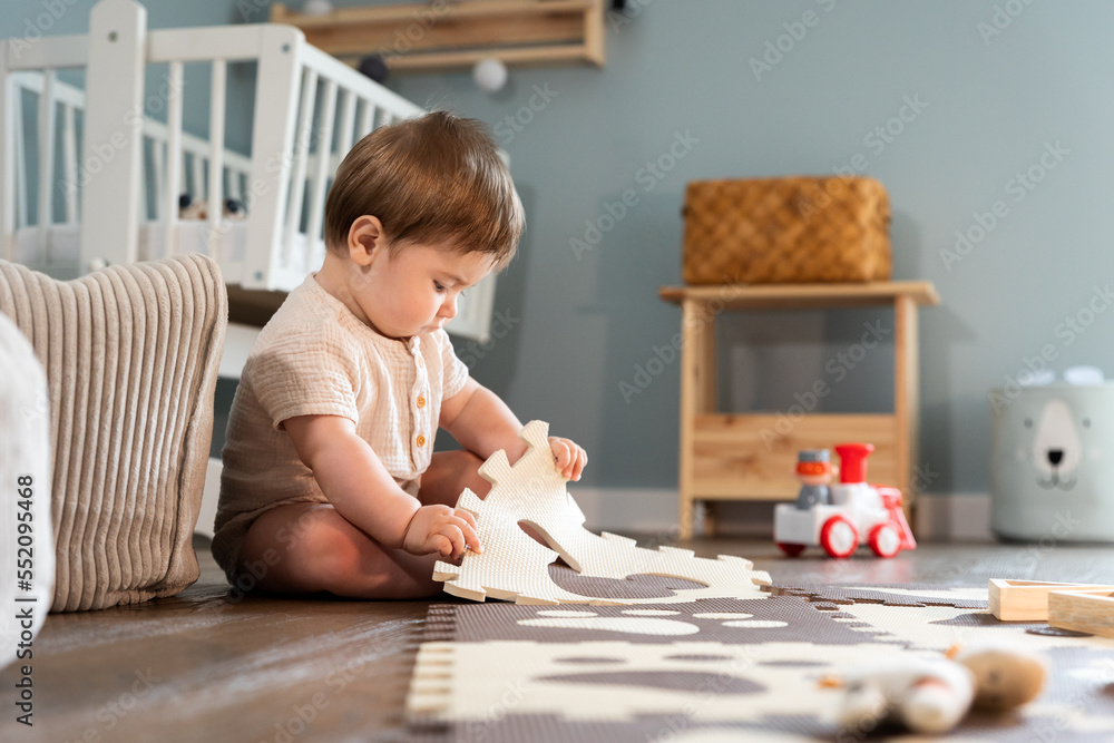 Cute happy baby boy playing toys in his child room