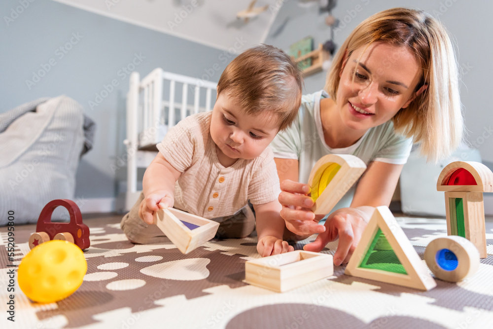 Loving family mom and baby boy playing together toys on floor in child room