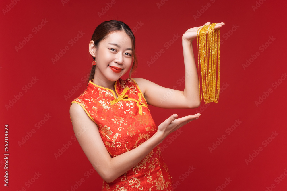 年轻的亚洲女性穿着红色背景的金色项链的qipao-cheonam连衣裙，代表中国人