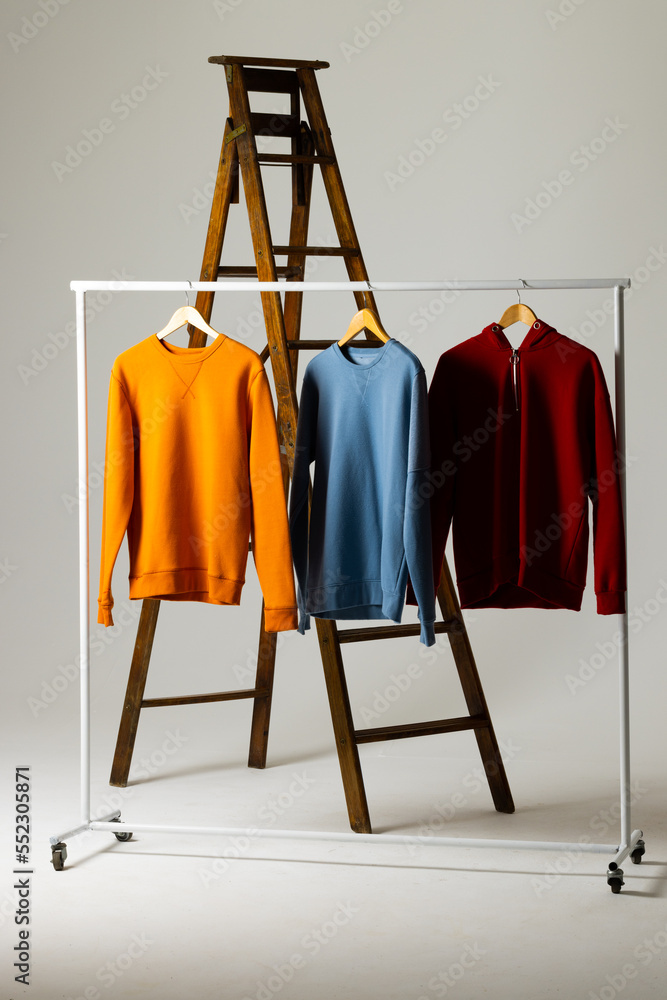 Coloured sweatshirts displayed on ladder and copy space on white background