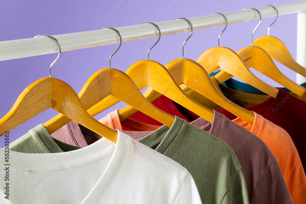 Coloured tshirts displayed on clothing rail and copy space on purple background