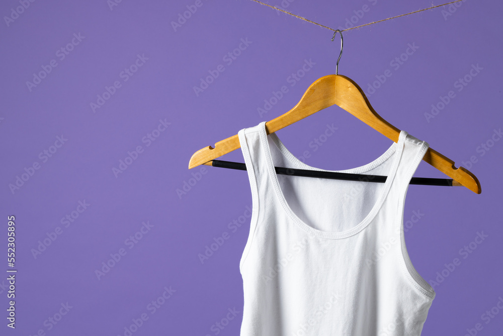 Tshirt hanging on coat hanger and copy space on purple background