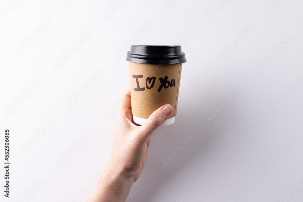 Hand holding takeaway coffee cup with i heart you text written on it, with copy space