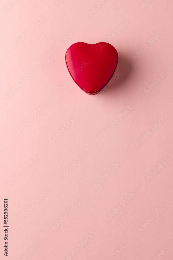 Overhead vertical image of red heart shaped box on pale pink background with copy space