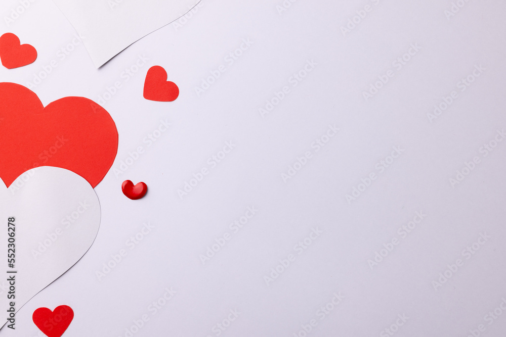 Red and white paper heart shapes on white background with copy space