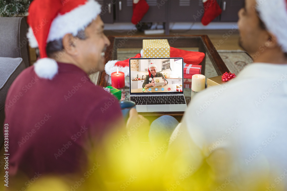 Senior biracial man and his adult son having christmas video call with senior caucasian man