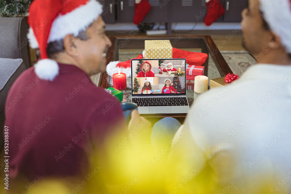 Senior biracial man and his adult son having christmas video call with diverse children