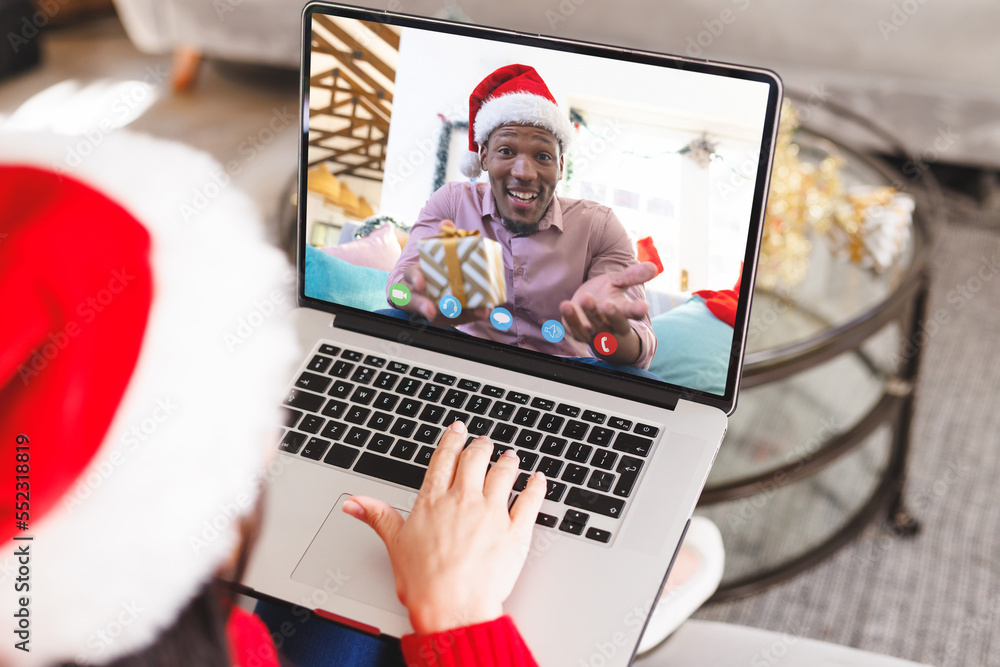 Caucasian woman having christmas video call with african american man