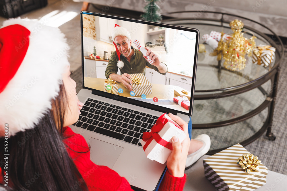 Caucasian woman having christmas video call with senior caucasian man