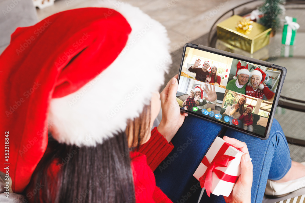 Caucasian woman having christmas video call with diverse people