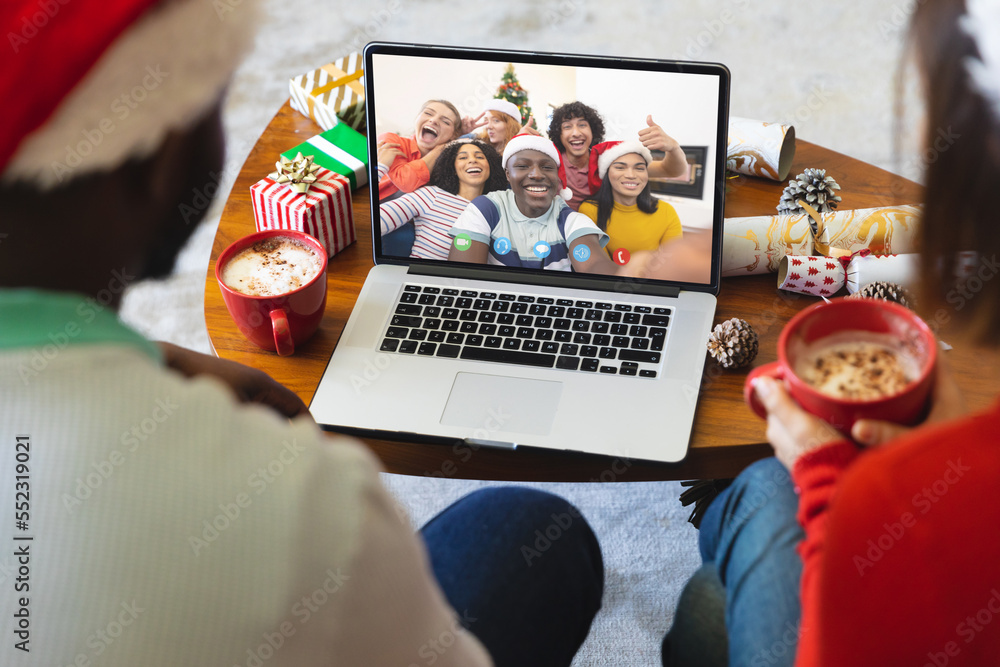 Diverse couple having christmas video call with diverse people