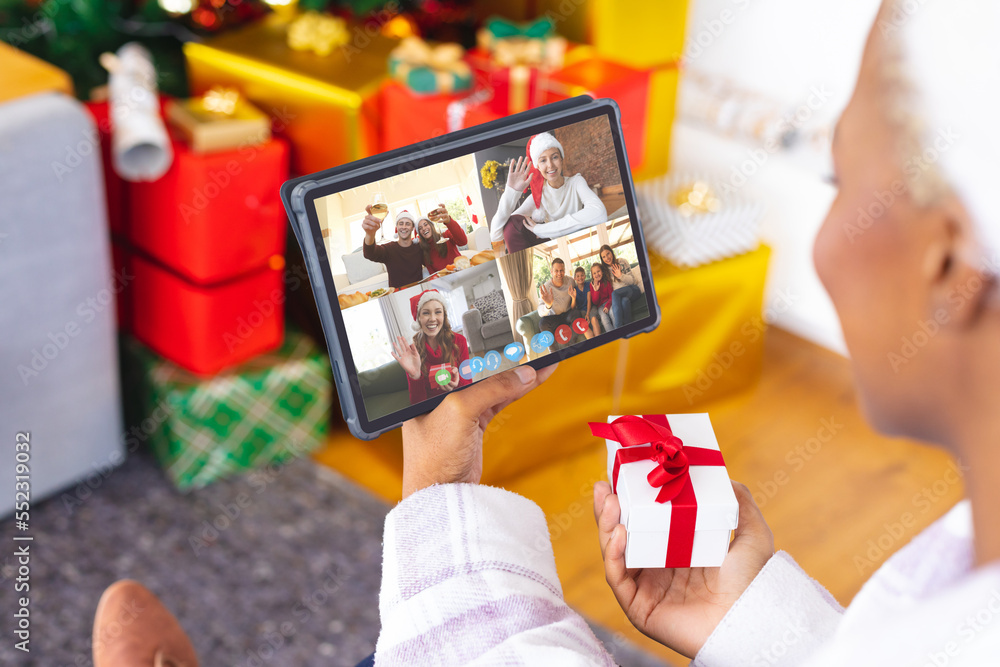 African american woman having christmas video call with diverse people