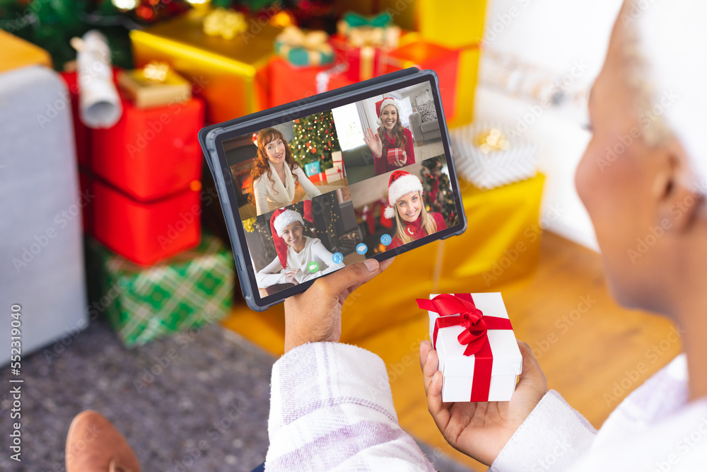 African american woman having christmas video call with diverse people