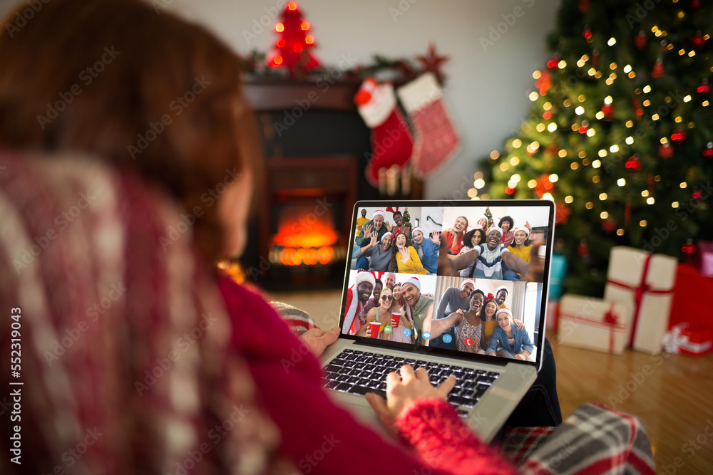 Caucasian woman having christmas video call with diverse people