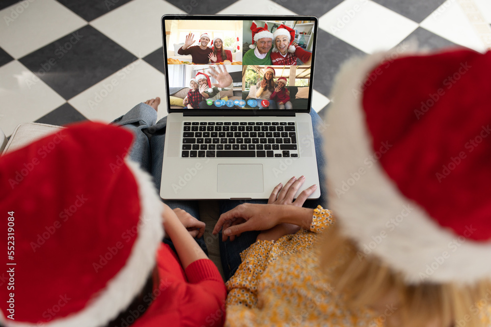 Caucasian mother and daughter in santa hats on christmas laptop video call with caucasian friends