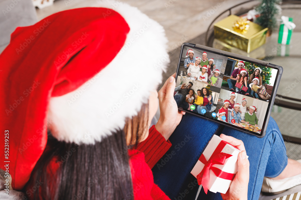 Caucasian woman with santa hat having video call with happy diverse friends