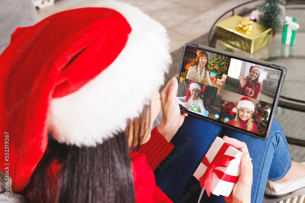 Caucasian woman with santa hat having video call with happy caucasian friends