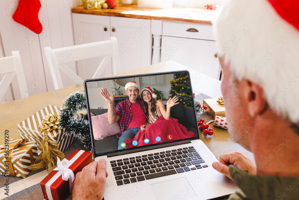 Caucasian man with santa hat having video call with happy caucasian couple