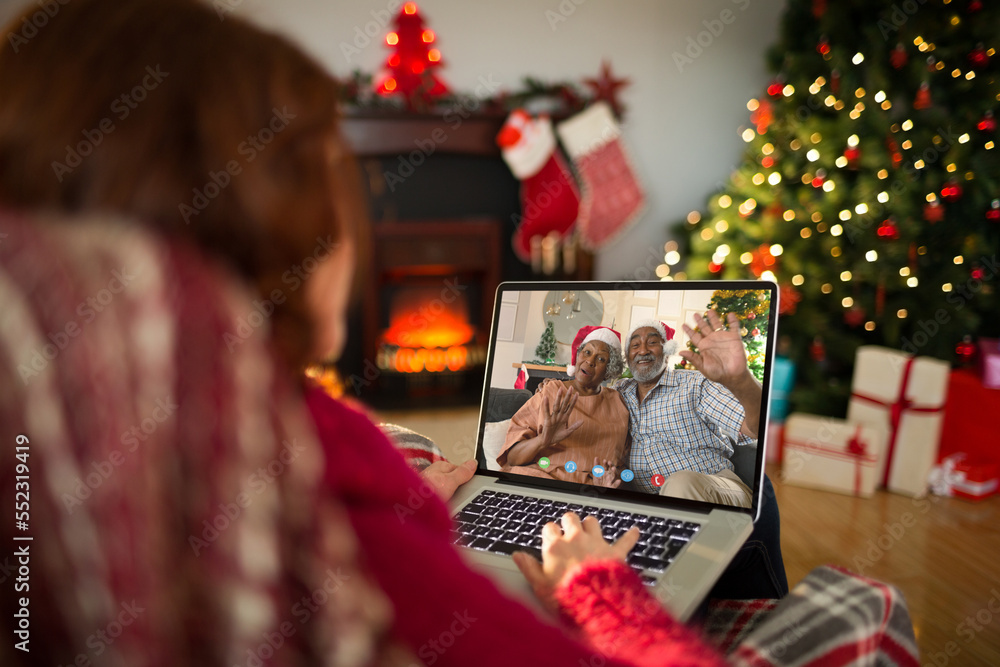 Caucasian woman with christmas decorations having video call with happy african american couple