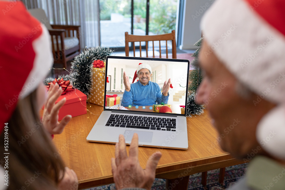 Caucasian father and daughter with santa hats having video call with happy biracial man