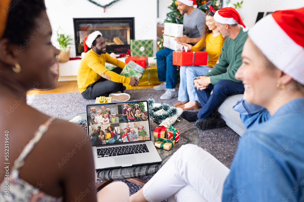 Diverse friends with santa hats having video call with happy diverse friends