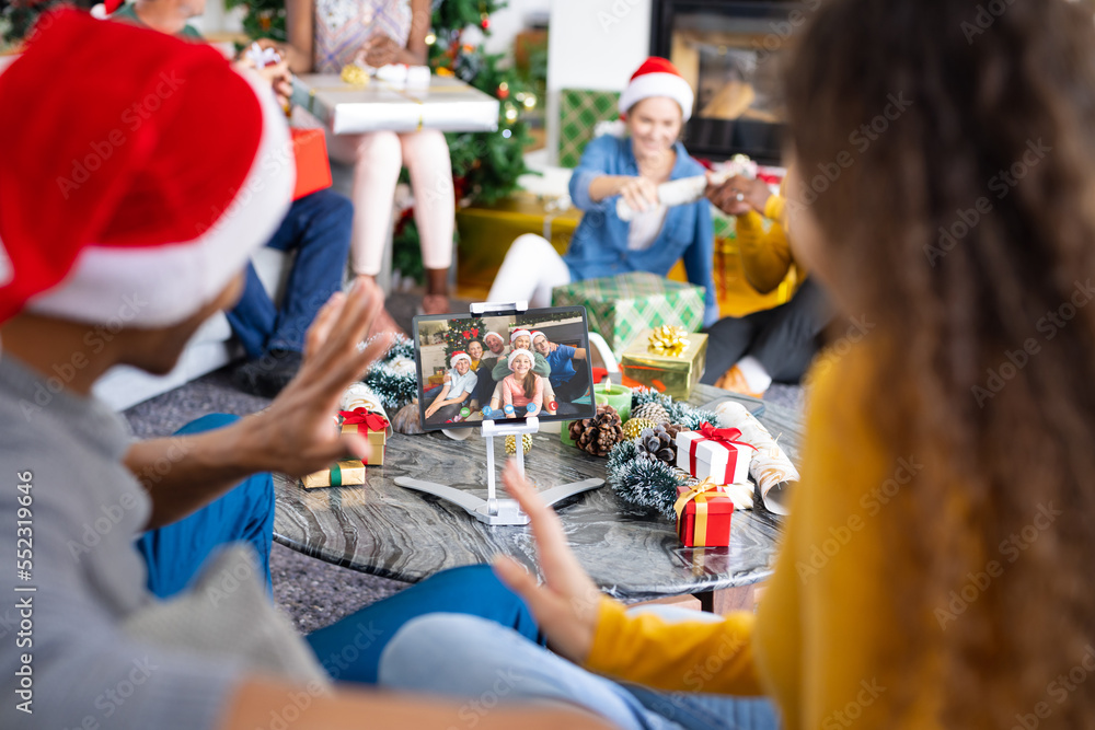 Diverse friends with santa hats having video call with happy caucasian family