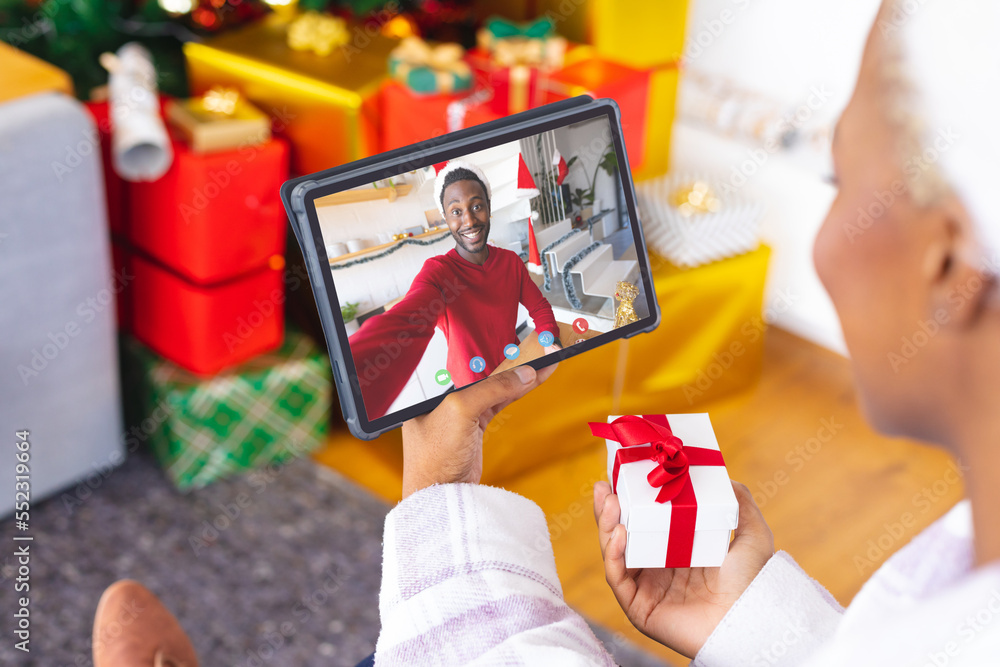 African american woman with christmas decorations having video call with happy african american man