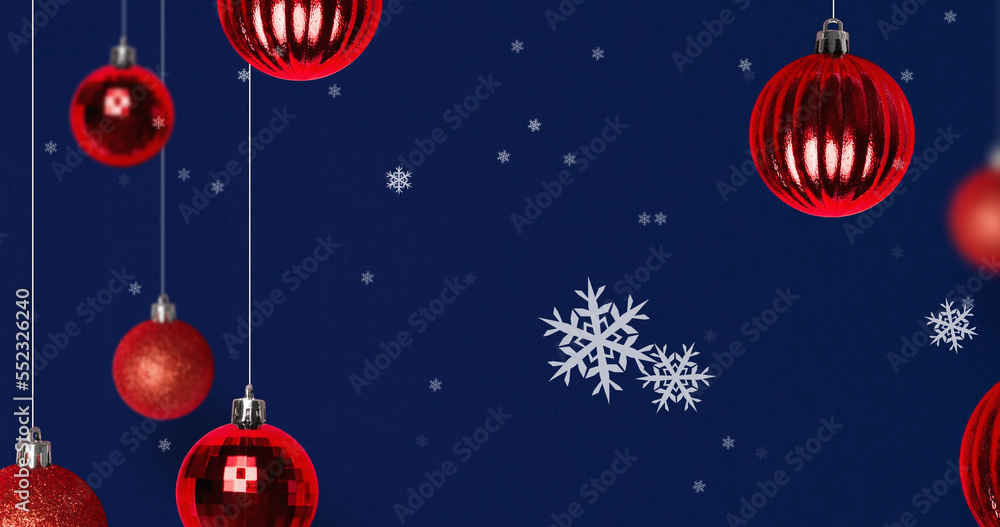 Image of snow falling over christmas bauble decorations on navy background