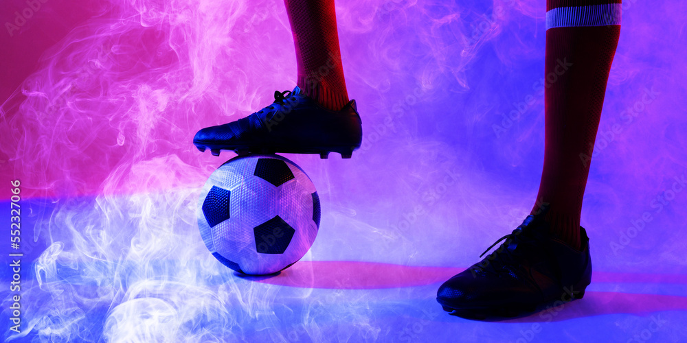 Low section of african american male player with leg on ball amidst smoky background