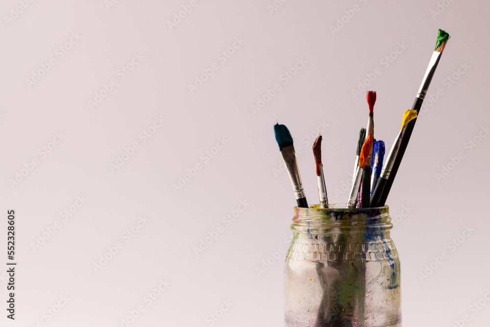 Image of close up of jar with paint brushes and copy space on cream background