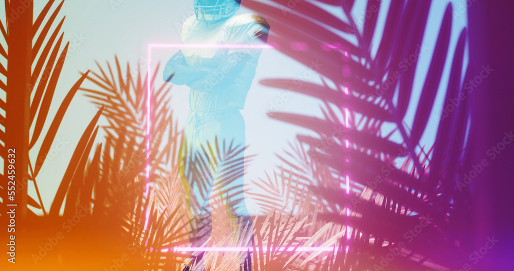 American football player with arms crossed standing by illuminates square and silhouette plants