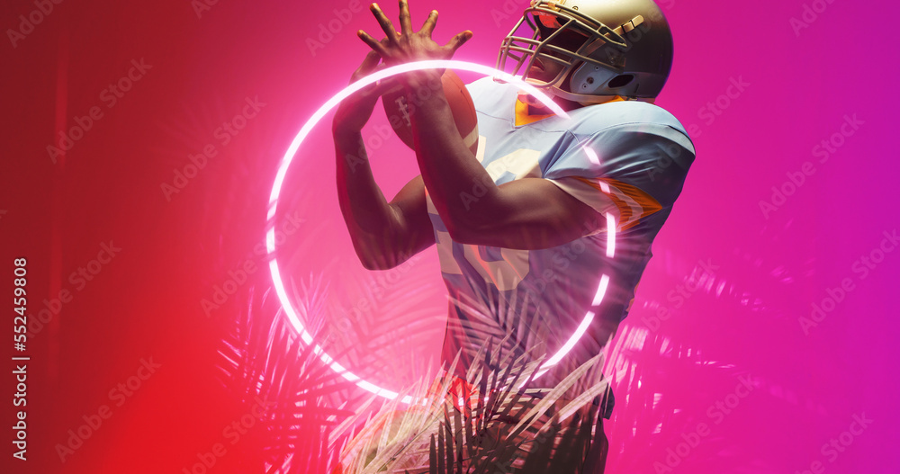 American football player catching ball while standing by illuminated circle and plants, copy space