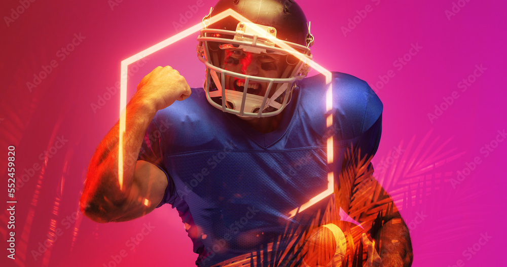 Cheerful american football player gesturing while standing by illuminated hexagon and plants