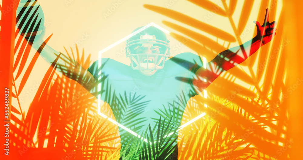 American football player with arms raised standing by illuminated hexagon and plants, copy space