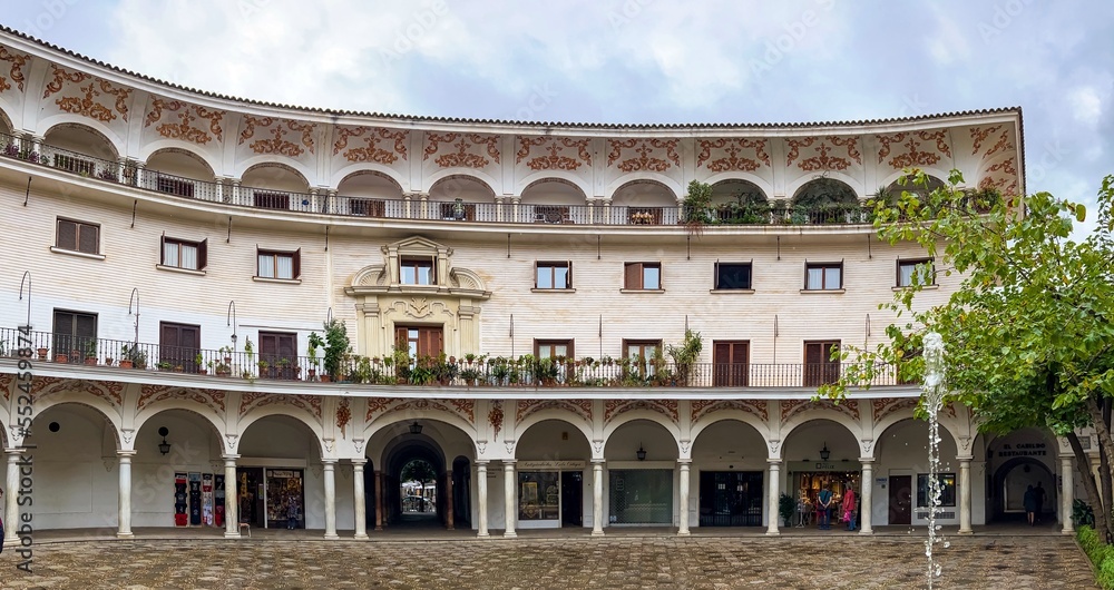 View of a semicircular building with an arched gallery and fountain