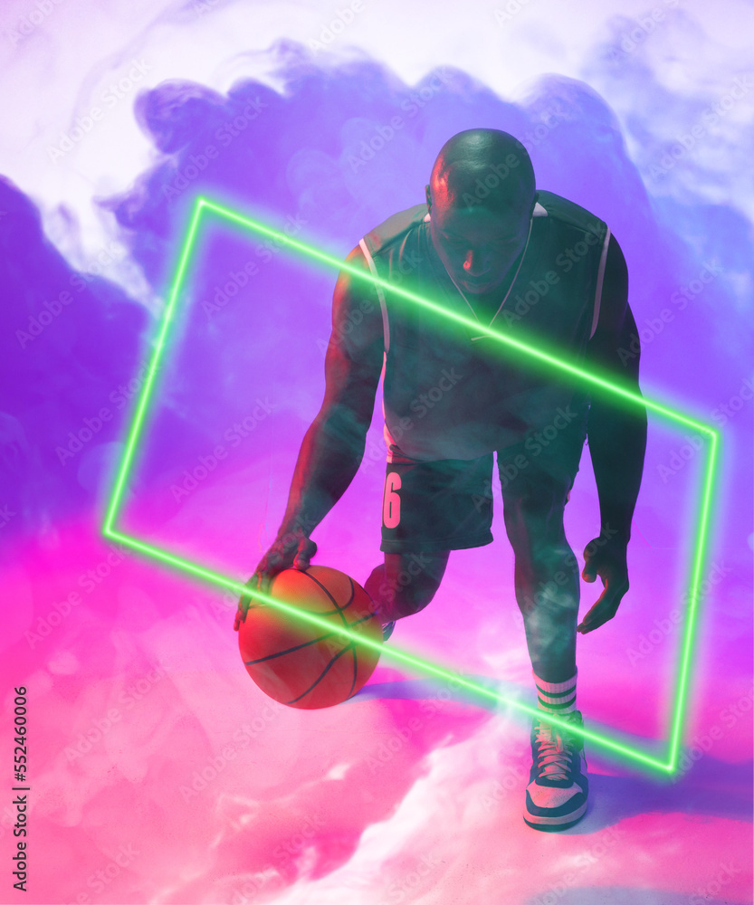 African american male basketball player dribbling ball by illuminated rectangle on smoky background