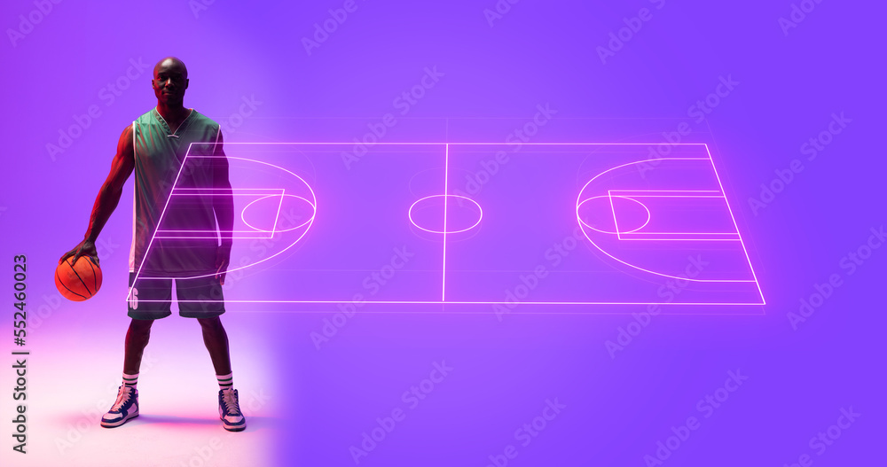 Full length of bald african american player with basketball standing by illuminated sports court