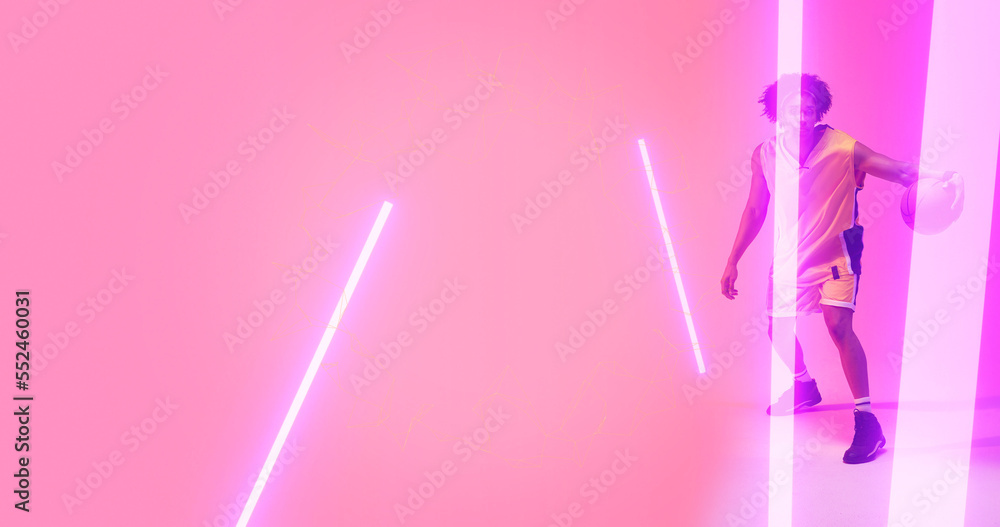 Composite of biracial basketball player dribbling ball with illuminated lights on pink background