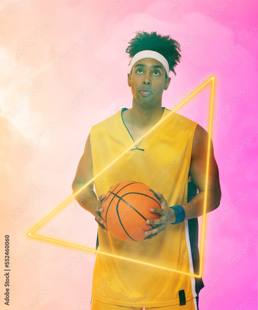 Composite of biracial male basketball player with ball standing by triangle over smoky background