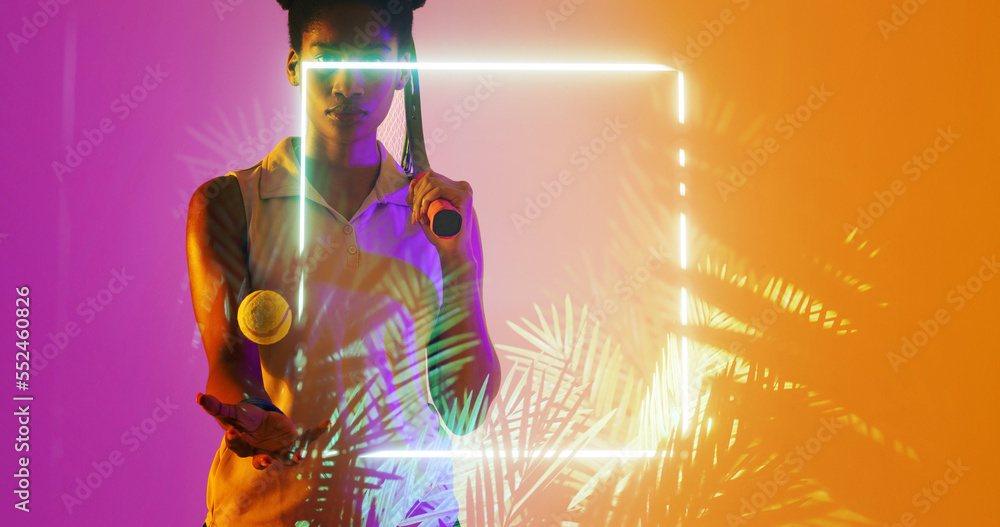 Biracial female tennis player with racket and ball standing by illuminated square and plants